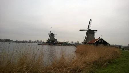 Ветрењаче у Zaanse Schans-у — симбол холандске традиције уз реку, у мирном сеоском пејзажу. - putujemo.org