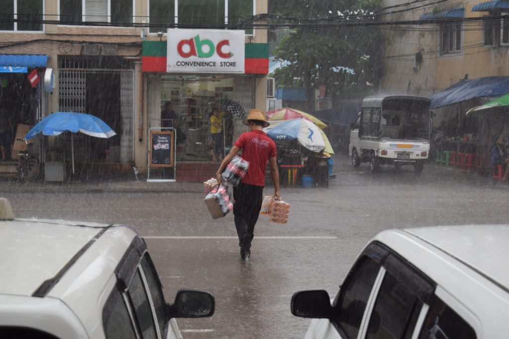 Радник носи пиће у продавницу без обзира на бесомучну кишу која пада